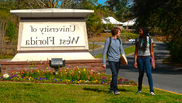 Students walking near UWF sign